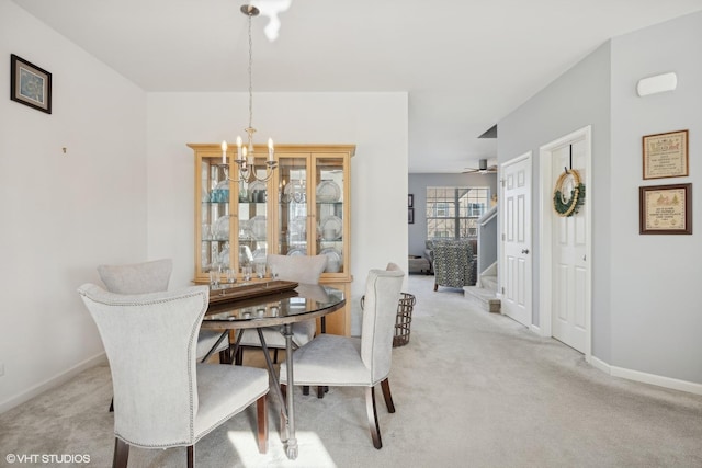 carpeted dining space featuring ceiling fan with notable chandelier