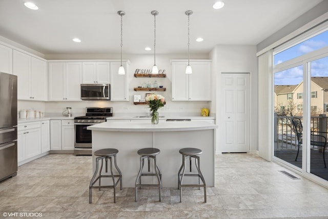 kitchen with appliances with stainless steel finishes, decorative light fixtures, a center island, and white cabinets