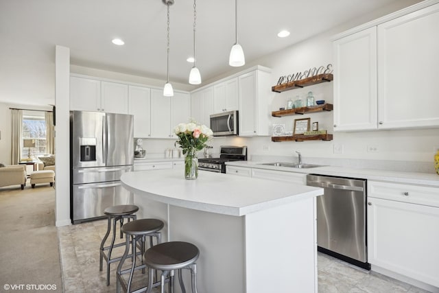 kitchen with a kitchen island, appliances with stainless steel finishes, decorative light fixtures, sink, and white cabinets