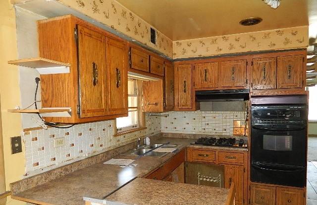 kitchen featuring tasteful backsplash, sink, kitchen peninsula, and black appliances