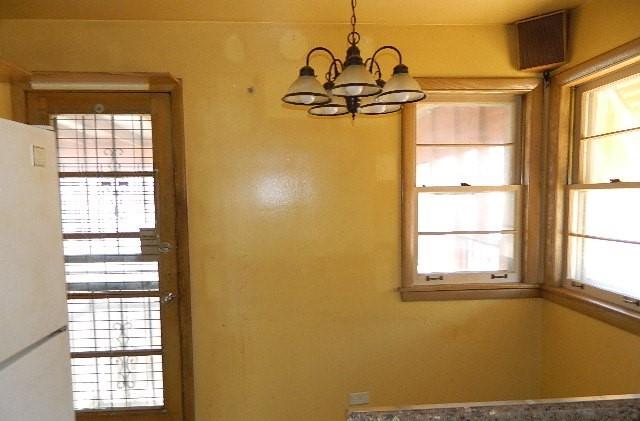 unfurnished dining area featuring an inviting chandelier and plenty of natural light