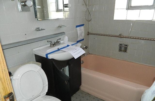 full bathroom featuring vanity, tiled shower / bath combo, and toilet