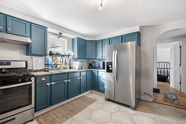 kitchen with stainless steel appliances, sink, blue cabinets, and light tile patterned floors