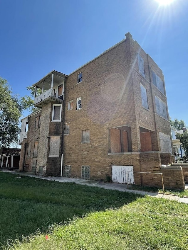 view of side of home with a balcony and a lawn