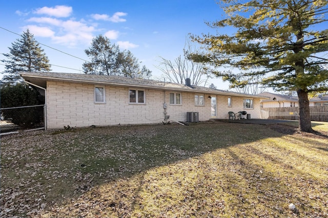 rear view of property featuring a patio area, stone siding, central AC unit, and fence