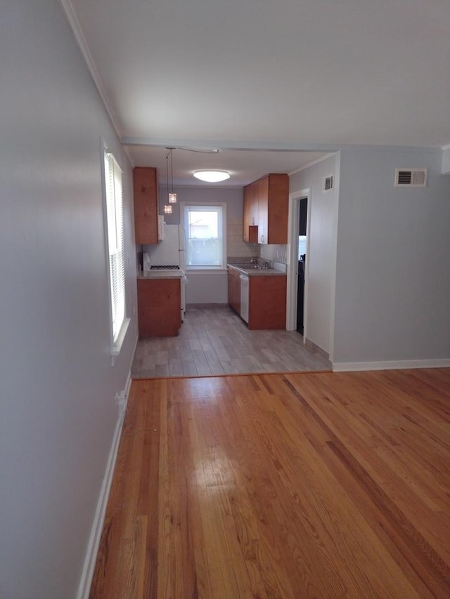 kitchen featuring tasteful backsplash, crown molding, pendant lighting, and light hardwood / wood-style flooring