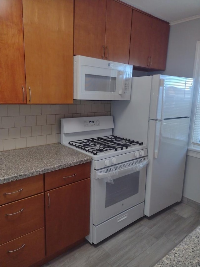 kitchen featuring white appliances, ornamental molding, light hardwood / wood-style floors, and backsplash