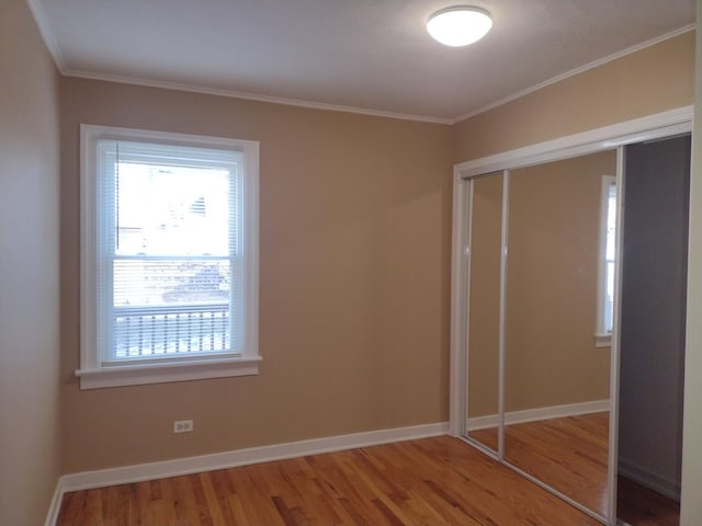 unfurnished bedroom with ornamental molding, hardwood / wood-style floors, and a closet