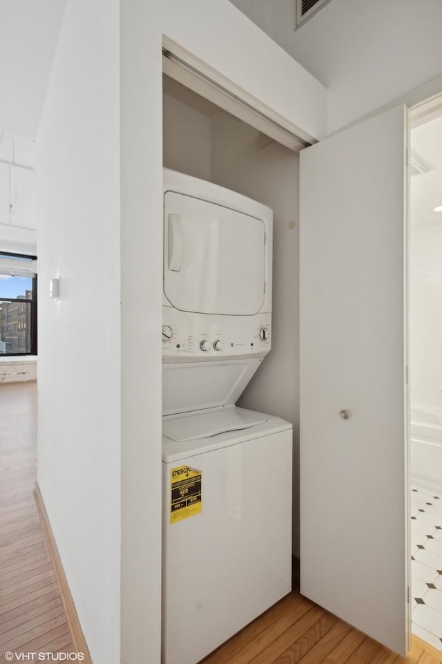 laundry area featuring stacked washer and dryer and light wood-type flooring