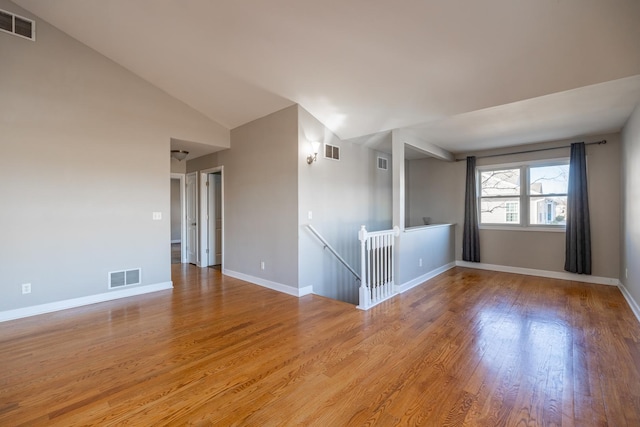 empty room with vaulted ceiling and light wood-type flooring