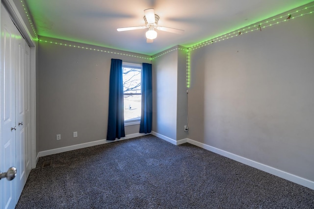 empty room with ceiling fan and dark carpet