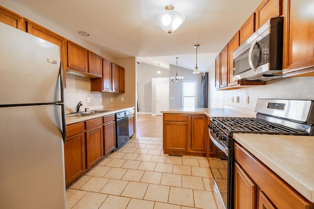 kitchen featuring lofted ceiling, sink, appliances with stainless steel finishes, an inviting chandelier, and hanging light fixtures