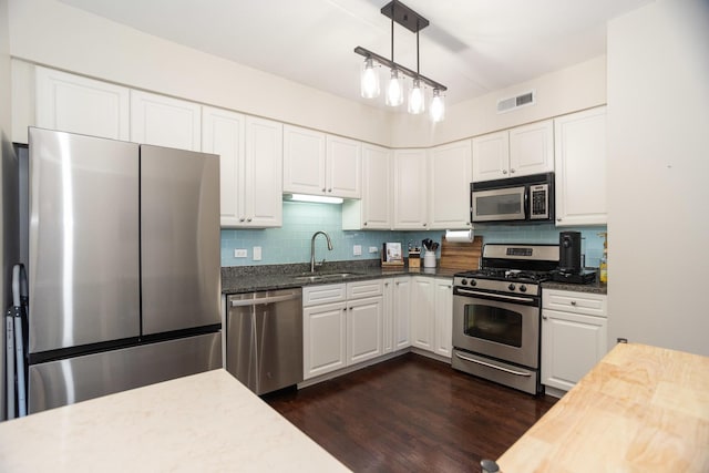 kitchen featuring sink, white cabinetry, hanging light fixtures, appliances with stainless steel finishes, and dark hardwood / wood-style floors