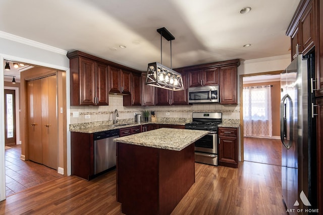 kitchen featuring dark wood-type flooring, stainless steel appliances, a center island, and hanging light fixtures