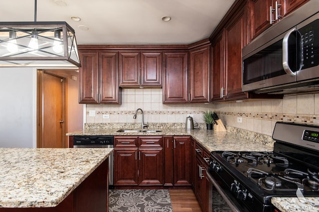 kitchen with sink, dark wood-type flooring, stainless steel appliances, light stone countertops, and decorative light fixtures