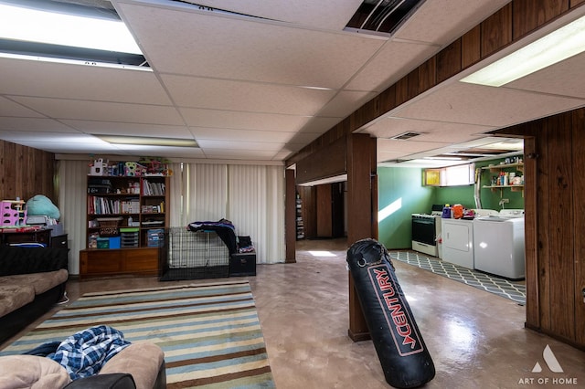 interior space featuring a drop ceiling, washer and dryer, and wood walls