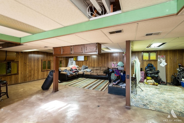 basement with a paneled ceiling and wood walls