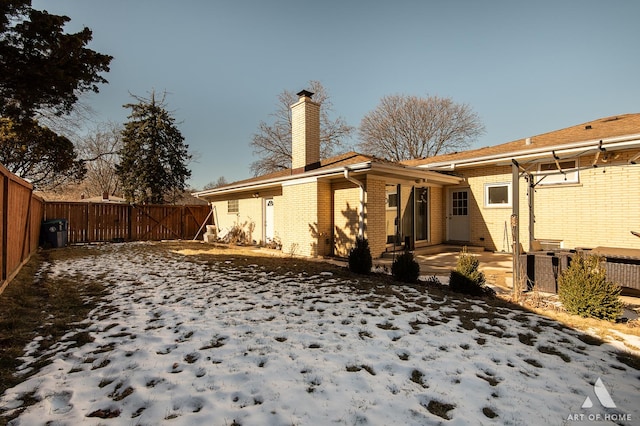 snow covered house featuring a patio area