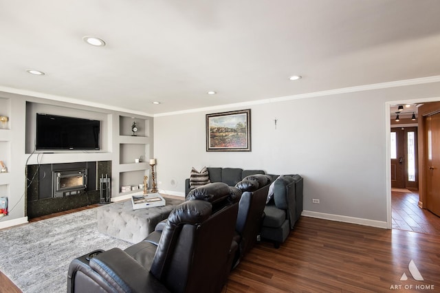 living room featuring ornamental molding, dark wood-type flooring, built in features, and a fireplace