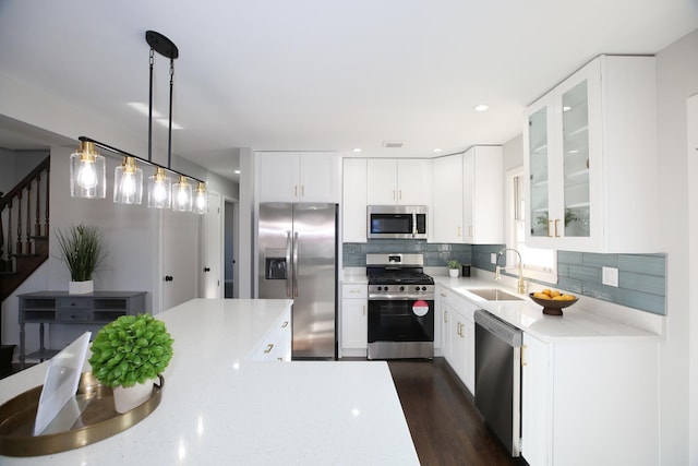 kitchen with sink, tasteful backsplash, pendant lighting, stainless steel appliances, and white cabinets