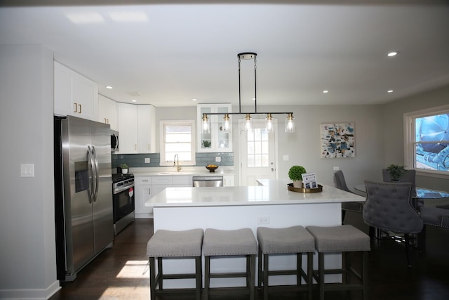 kitchen featuring sink, white cabinets, hanging light fixtures, a center island, and stainless steel appliances