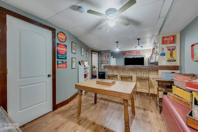 interior space featuring bar area, a paneled ceiling, ceiling fan, and light wood-type flooring