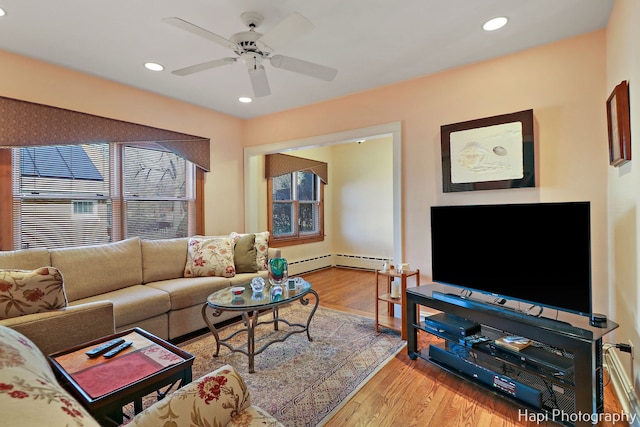 living room featuring ceiling fan, a baseboard radiator, and light wood-type flooring