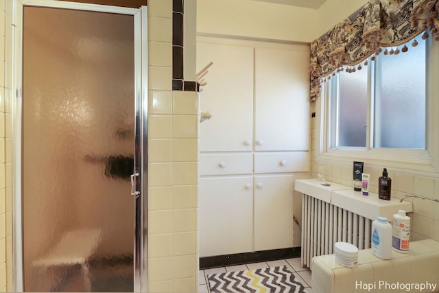 bathroom with radiator, tile patterned floors, a shower with door, and a healthy amount of sunlight