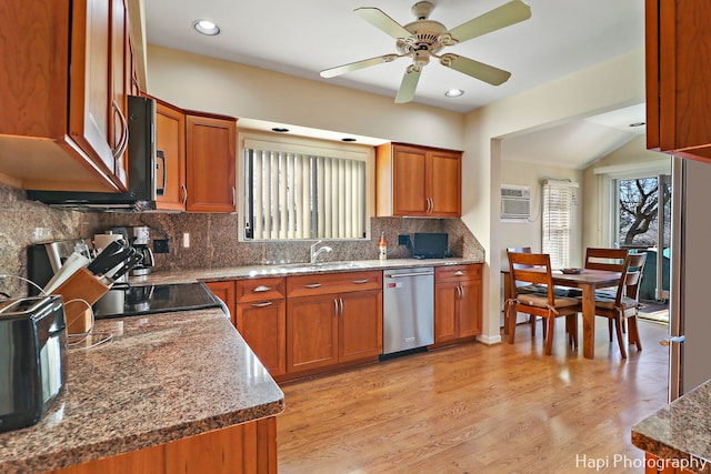 kitchen featuring sink, light hardwood / wood-style flooring, dark stone countertops, stainless steel dishwasher, and decorative backsplash