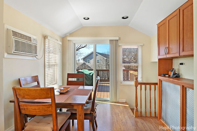 dining room with lofted ceiling, a wall mounted air conditioner, and light wood-type flooring