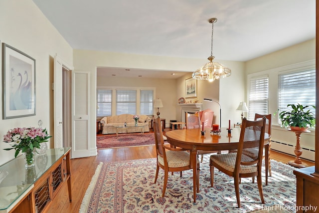 dining room with light hardwood / wood-style floors, a chandelier, and baseboard heating