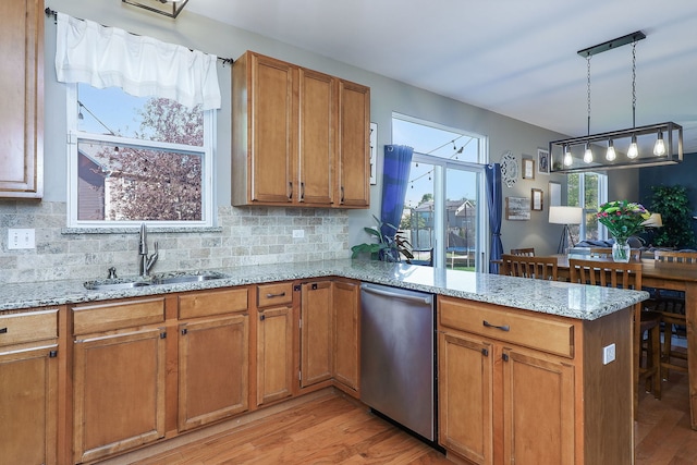 kitchen with decorative light fixtures, sink, backsplash, light stone counters, and kitchen peninsula