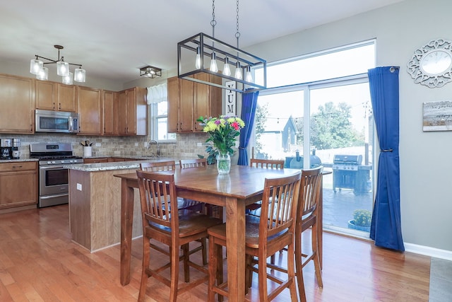 kitchen featuring pendant lighting, sink, appliances with stainless steel finishes, tasteful backsplash, and light hardwood / wood-style floors