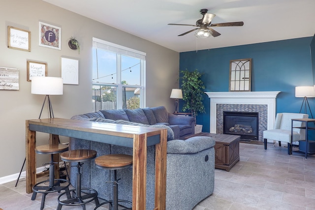 living room with ceiling fan and a tiled fireplace