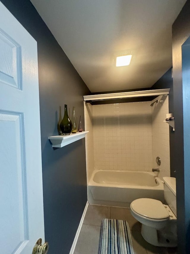 bathroom featuring tile patterned flooring, tiled shower / bath, and toilet