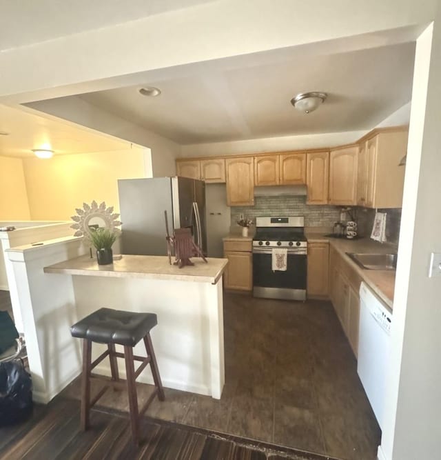 kitchen with light brown cabinetry, a kitchen breakfast bar, kitchen peninsula, stainless steel appliances, and decorative backsplash