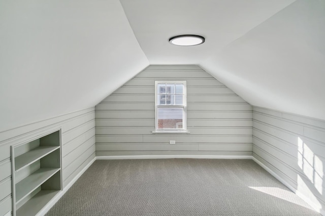 bonus room featuring lofted ceiling, carpet floors, and wood walls