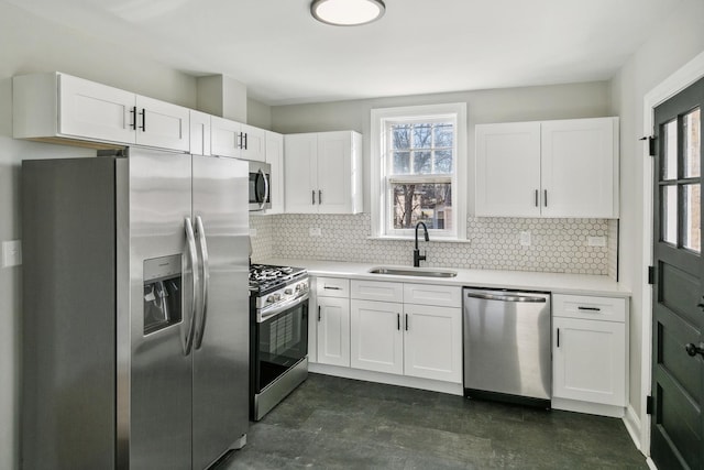 kitchen with a sink, appliances with stainless steel finishes, white cabinetry, and light countertops