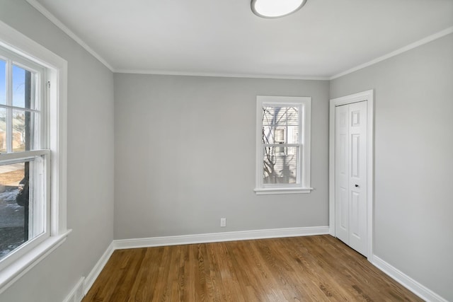 spare room featuring baseboards, ornamental molding, and wood finished floors