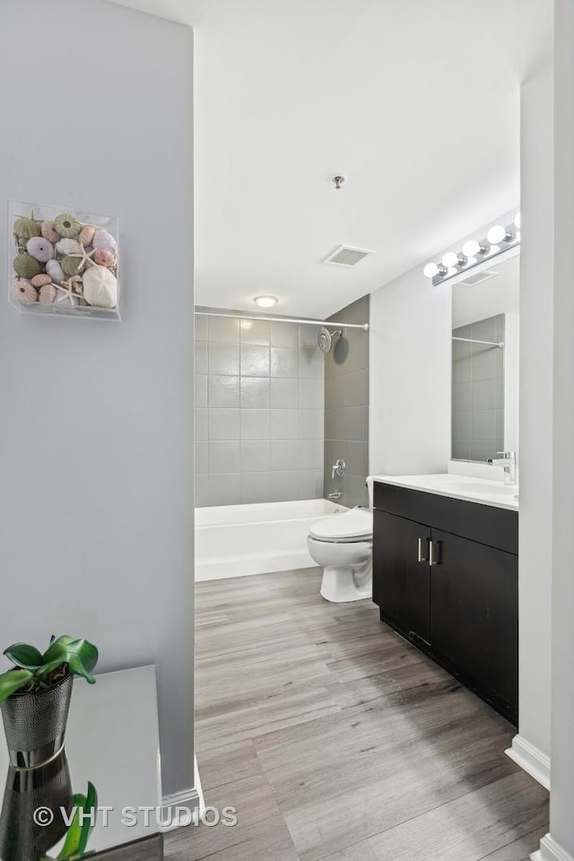 full bathroom featuring hardwood / wood-style flooring, vanity, toilet, and tiled shower / bath combo