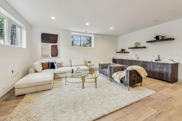 living room featuring indoor wet bar, light hardwood / wood-style floors, and a healthy amount of sunlight