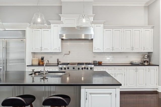 kitchen with built in fridge, tasteful backsplash, sink, white cabinets, and range