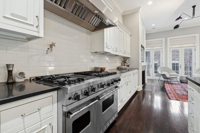 kitchen featuring dark hardwood / wood-style floors, white cabinets, range with two ovens, ornamental molding, and wall chimney exhaust hood