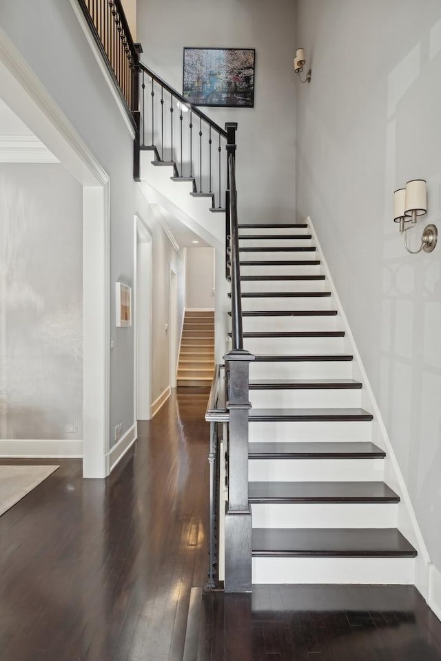 stairway with hardwood / wood-style flooring and a high ceiling