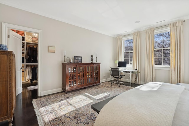 bedroom with a walk in closet, ornamental molding, dark hardwood / wood-style flooring, and a closet