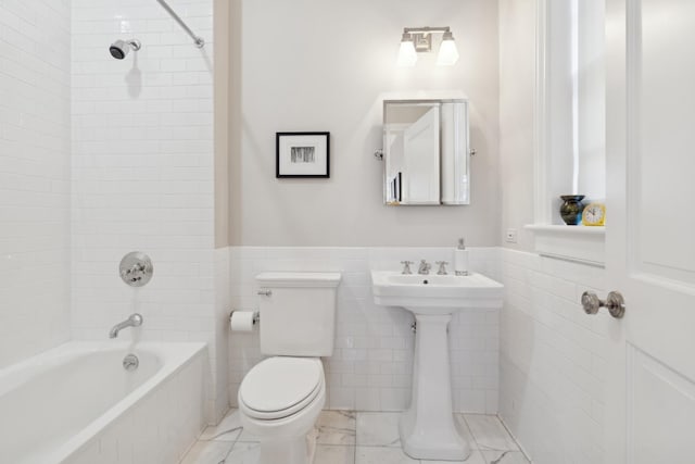 full bathroom with tiled shower / bath, toilet, sink, and tile walls