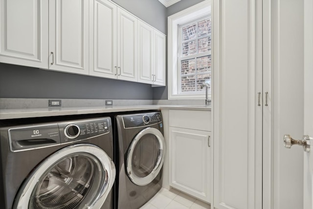 washroom with sink, light tile patterned floors, washing machine and dryer, and cabinets