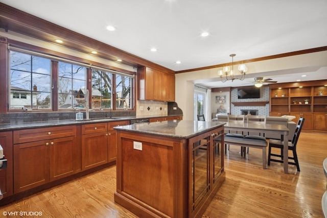 kitchen with dark stone countertops, a brick fireplace, light hardwood / wood-style flooring, and a kitchen island