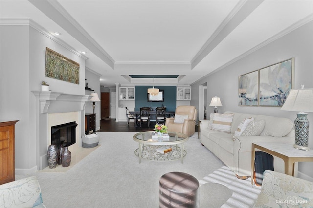 living room with ornamental molding, a premium fireplace, and a raised ceiling