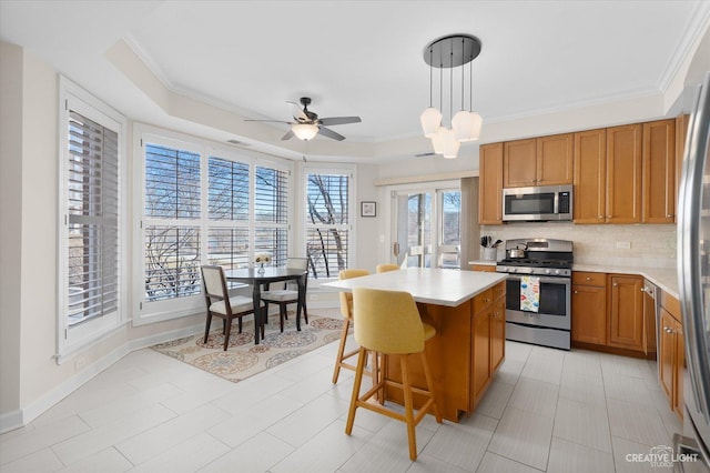 kitchen with pendant lighting, backsplash, a center island, a tray ceiling, and stainless steel appliances